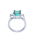 A detailed view of an emerald and princess-cut diamond ring, highlighting the top, side gallery, and band.