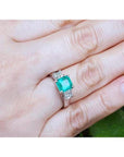 14k white gold engagement ring with a vibrant emerald center stone and princess cut diamonds.
