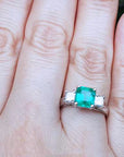 Emerald ring on a finger with a natural background.