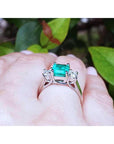 1.62 carat emerald engagement ring with princess cut diamonds in 14k white gold on a hand.