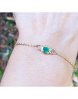 14K yellow gold solitaire bracelet with a deep green Colombian emerald on a wrist.