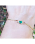 14K yellow gold solitaire bracelet with a deep green Colombian emerald on a wrist.