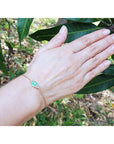 Women's 14k yellow gold bracelet with a 0.85 ct emerald and six natural diamonds on a wrist.