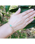 Women's 14k yellow gold bracelet with a 0.85 ct emerald and six natural diamonds on a wrist.