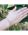 Women's 14k yellow gold bracelet with a 0.85 ct emerald and six natural diamonds on a wrist.