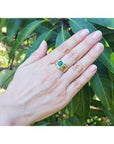 Men's 1.57 ct deep green Colombian emerald solitaire ring, bezel set in 14K yellow gold on a hand.