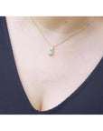 Emerald solitaire pendant necklace in 14K yellow gold on a woman's chest.