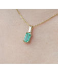1.31 ct. emerald solitaire pendant in 14K yellow gold on a delicate chain, worn on a person.
