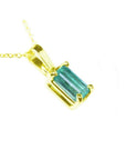 A 14k yellow gold solitaire pendant featuring a Muzo-born natural Colombian emerald in a prong setting.