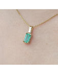 1.31 ct. emerald solitaire pendant in 14K yellow gold on a delicate chain, worn on a person.