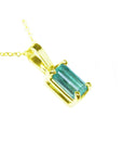 A yellow gold emerald solitaire pendant showing its top and side gallery profile.