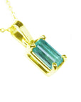 A yellow gold emerald solitaire pendant showing its top and side gallery profile.