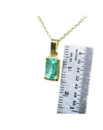 1.31 ct emerald solitaire pendant in 14K yellow gold with a ruler for scale.