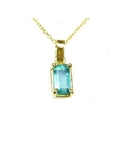 This solitaire emerald pendant displays the topside with a yellow gold frame on a chain.
