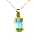 This solitaire emerald pendant displays the topside with a yellow gold frame on a chain.