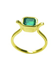 A partial profile of a solitaire emerald ring bezel set in yellow gold.