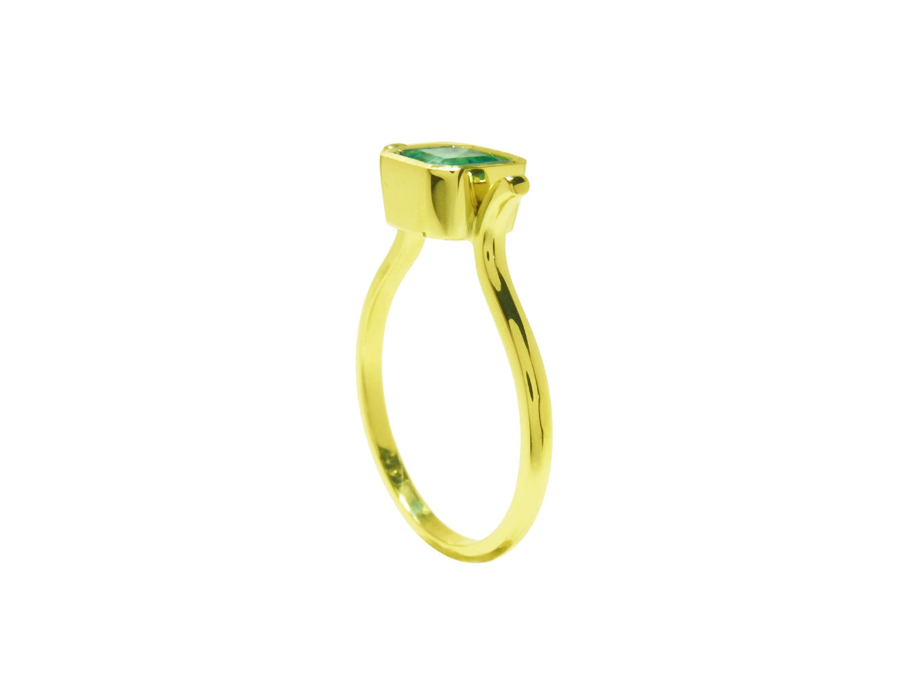 A side perspective of a solitaire emerald ring bezel set in yellow gold