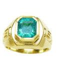 A 14k yellow gold men's emerald solitaire ring bezel set with side Greek decoration.