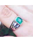 This 18k white gold men's natural colombian emerald solitaire ring is a bezel set tyle worn on a finger.