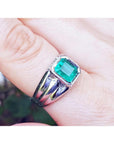This 18k white gold men's natural colombian emerald solitaire ring is a bezel set tyle worn on a finger.