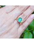 2.14 ct. rectangular Colombian emerald solitaire ring, bezel set in 14K yellow gold on a hand.