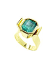 This emerald solitaire ring is on a tilted position, displaying the top bezel and side profile.