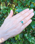 Colombian emerald solitaire silver ring with a square-cut deep bluish-green gemstone on a woman's hand.