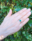 Colombian emerald solitaire silver ring with a square-cut deep bluish-green gemstone on a woman's hand.