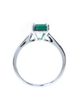 A lateral view of a solitaire sterling silver ring with a natural colombian emerald on a white background