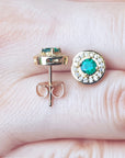 Gold earrings with emerald stones on a hand.