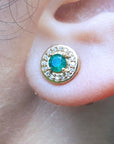 Close-up of a 14k yellow gold emerald stud earring on an ear.