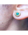 14k yellow gold emerald halo diamond stud earring on an ear.