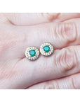 14k yellow gold emerald halo diamond stud earrings with deep bluish-green round cut emeralds.