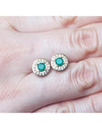 14k yellow gold emerald halo diamond stud earrings with deep bluish-green round cut emeralds.