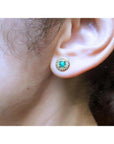 14k yellow gold emerald halo stud earring with round deep bluish-green emerald and diamond accents.