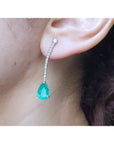 Close-up of a colombian emerald teardrop earring on a person's ear.