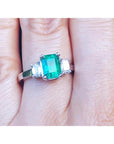 Women's emerald three stone ring side diamonds on a finger