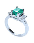 A 18k white gold emerald ring three stone on a half side profile view.