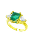 A women's colombian emerald ring with side trillion cut diamonds in 18k yellow gold.