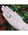 18k yellow gold ring with a GIA 4.16 ct emerald and two trillion side diamonds on a hand.