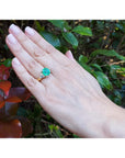18k yellow gold ring with a GIA 4.16 ct emerald and two trillion side diamonds on a hand.