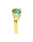18k yellow gold ring with a large natural colombian emerald and two trillion side diamonds.