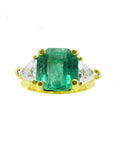 18k yellow gold ring with a rectangular green emerald and two trillion side diamonds.