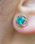 Close-up of a tulip emerald stud earring on an ear.