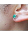 Close-up of an ear wearing a 14k white gold emerald tulip stud earring underside view.
