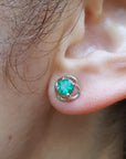 Close-up of an ear wearing a Colombian emerald stud earring.