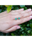 Tulip emerald stud earrings, 1.03 ct, 14K white gold, on a hand against green foliage.