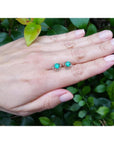 Tulip emerald stud earrings, 1.03 ct, 14K white gold, on a hand against green foliage.