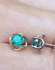 Colombian emerald tulip stud earrings on a person's finger.