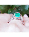 Anillo de compromiso de oro blanco con esmeralda colombiana central y diamantes trapezoide.
